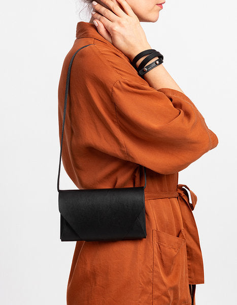 Pochette-portefeuille en cuir noir Stella Soomlais portée courte à la hanche, mannequin de trois quarts