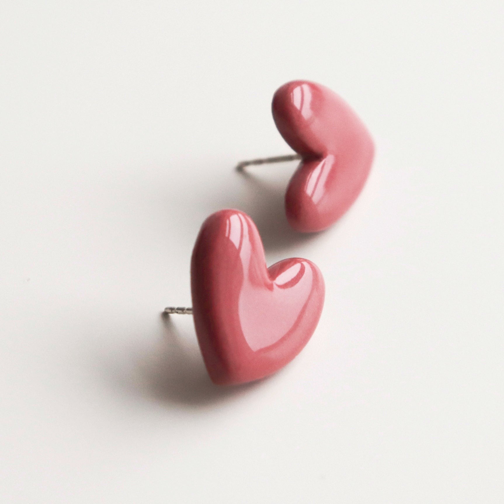 Puces d'oreilles cœur en porcelaine rose, vue verticale