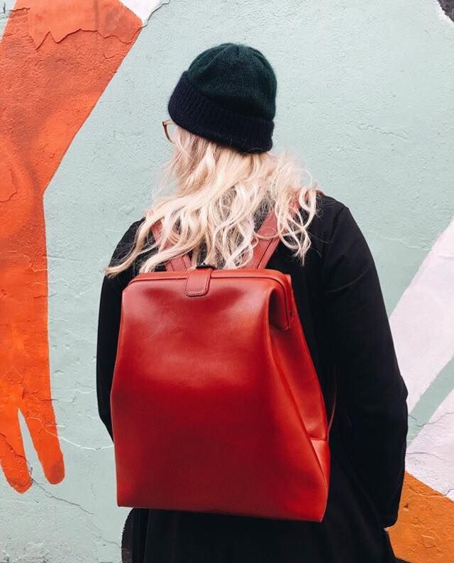 Sac à dos en cuir rouge RR, porté en lifestyle devant un mur street art