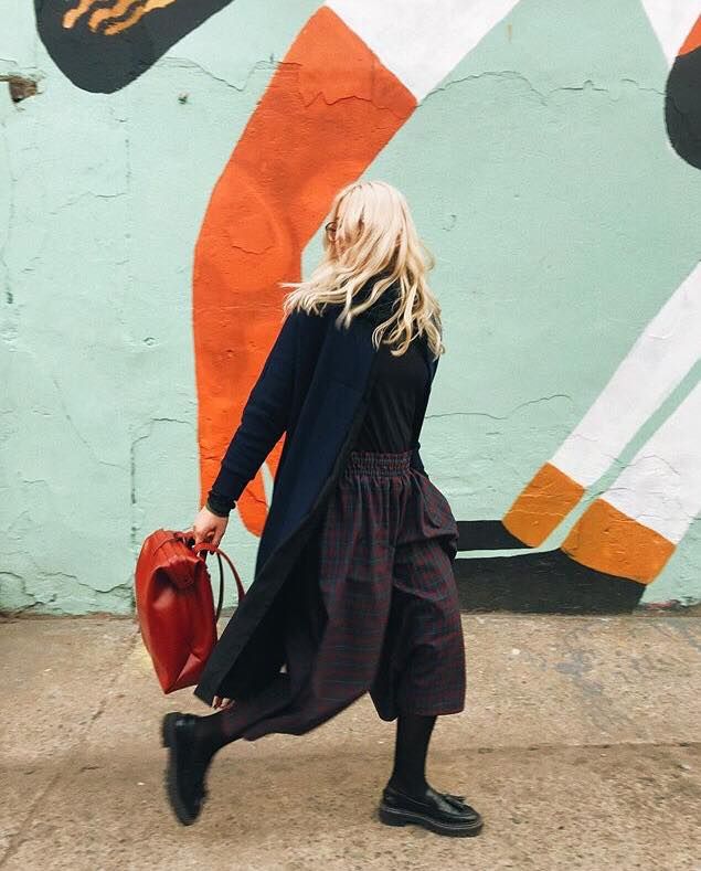 Sac à dos en cuir rouge RR, vue latérale devant un mur street art coloré