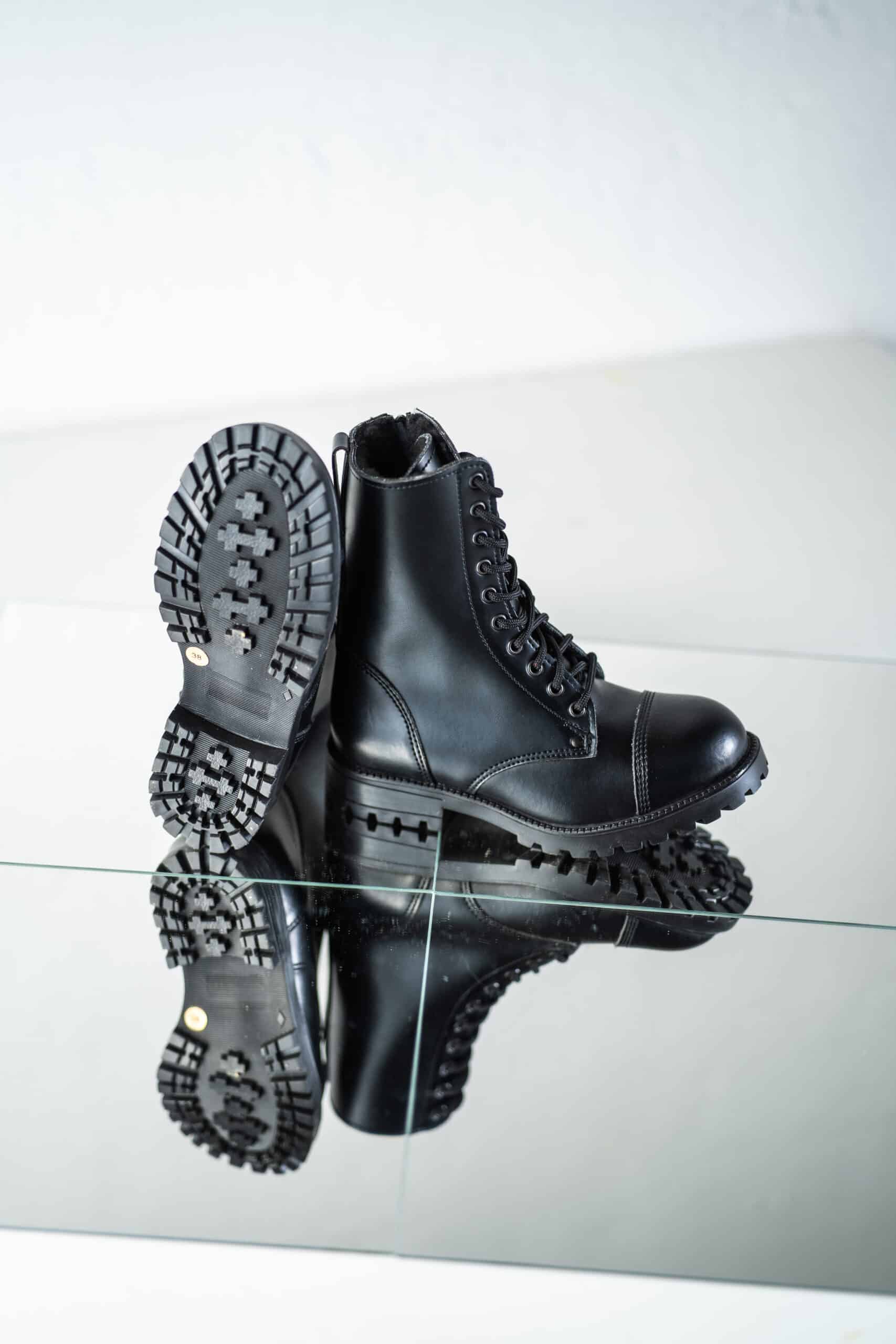 Bottines d'hiver en cuir noir à semelle crantée, mise en scène sur miroir