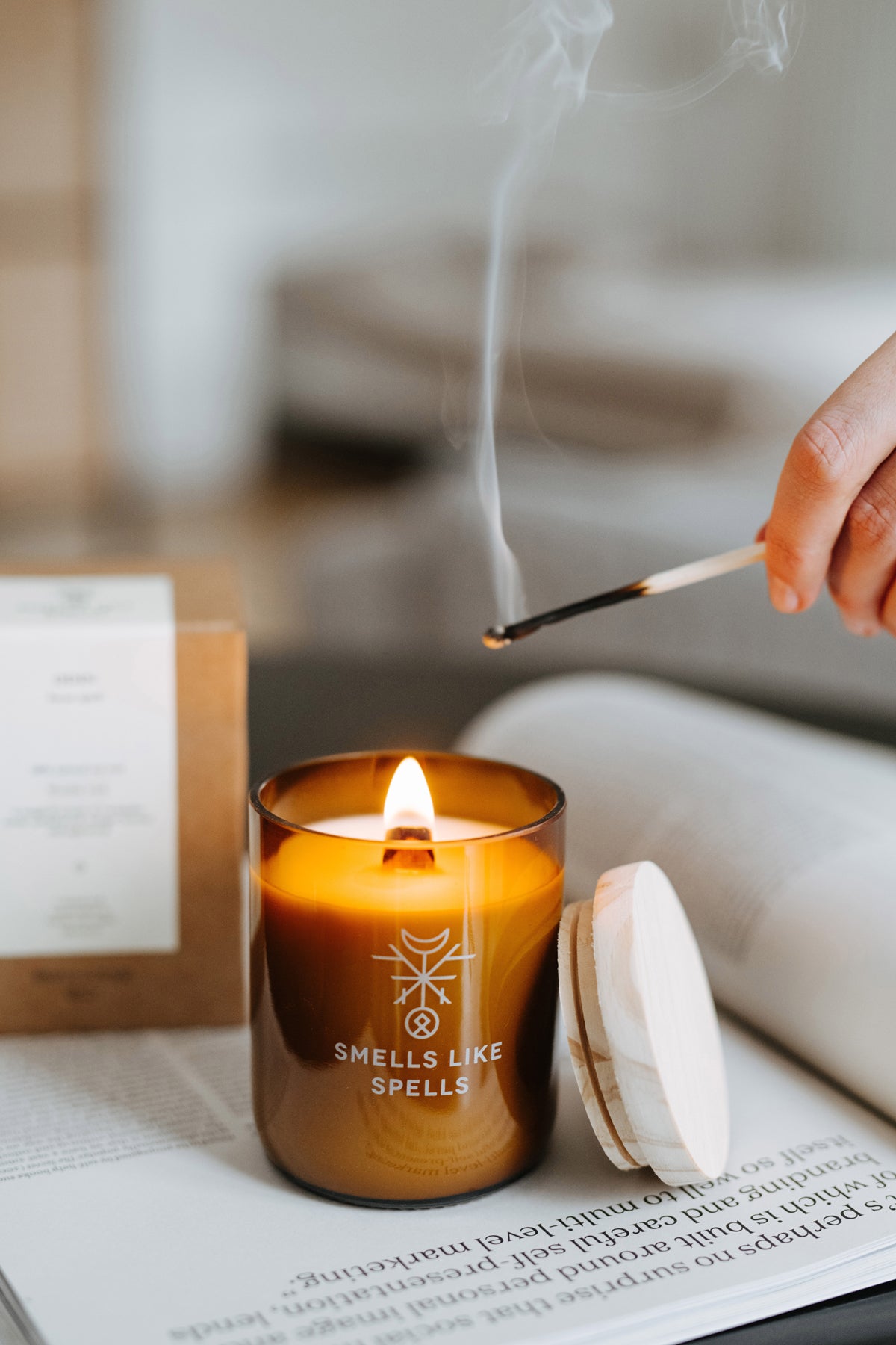 Bougie parfumée en verre ambré Smells Like Spells allumée à la main avec flamme, vue lifestyle