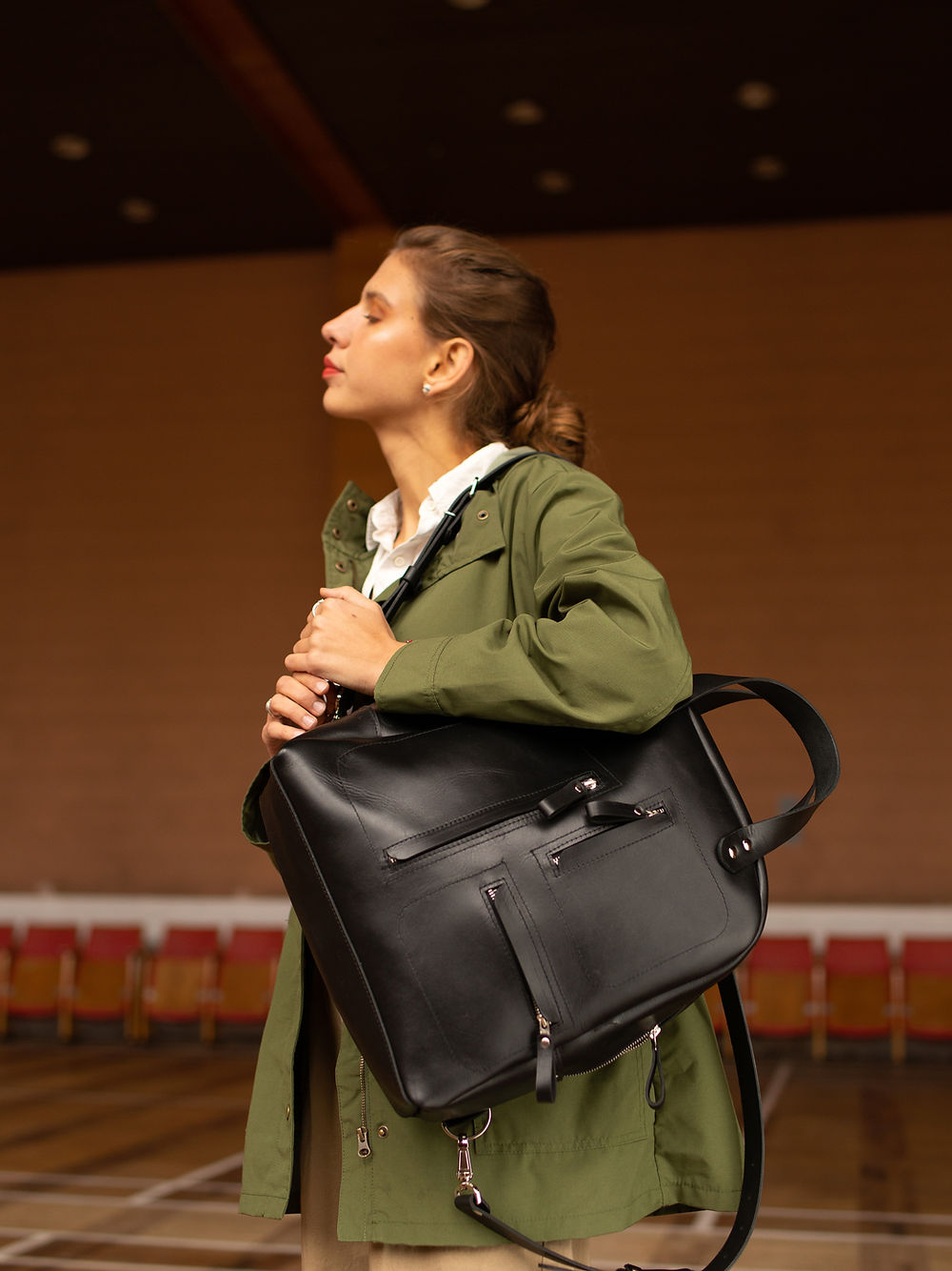 Sac à dos en cuir noir porté en main, photo lifestyle