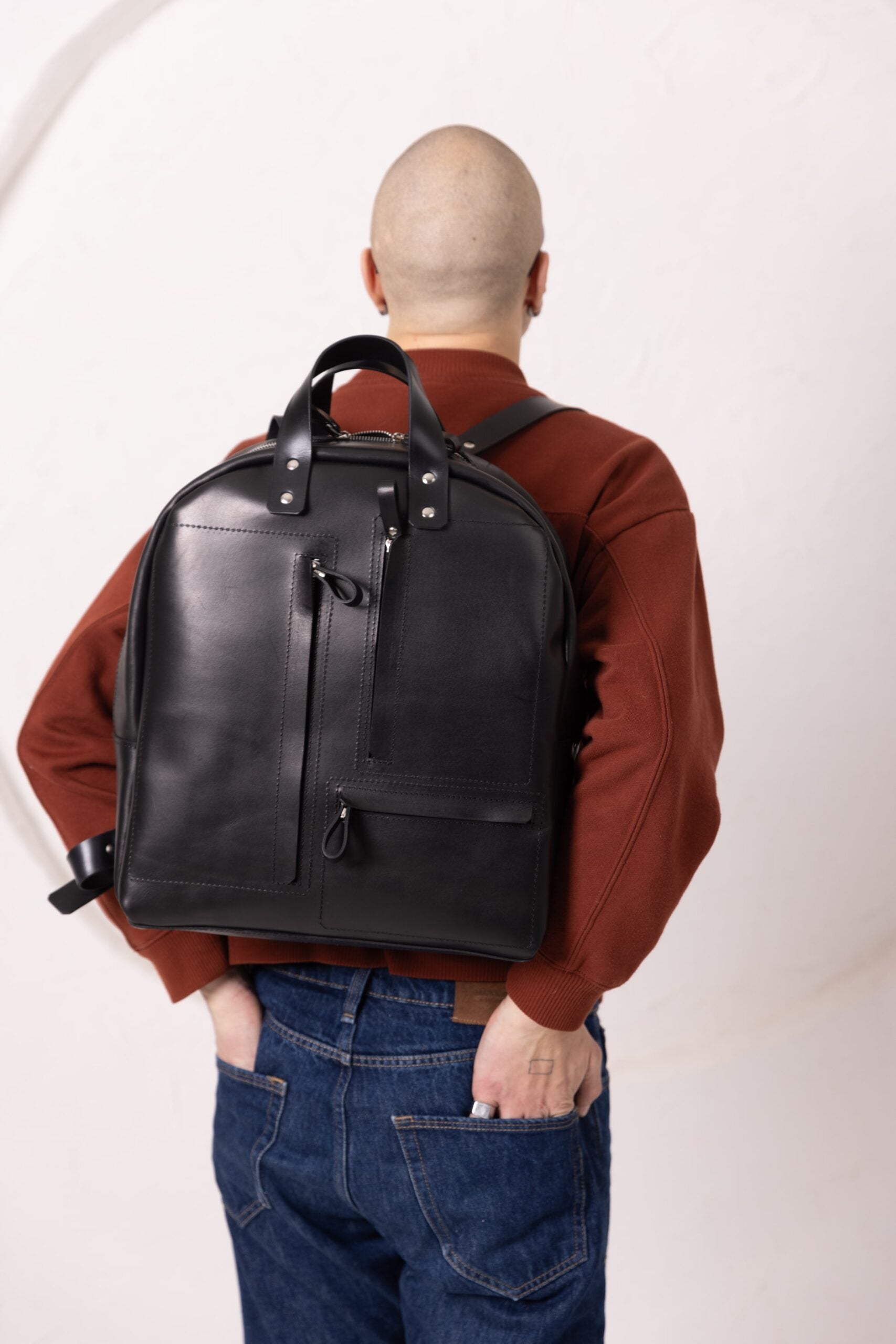 Sac à dos en cuir noir à structure carrée, vue de face sur fond studio blanc