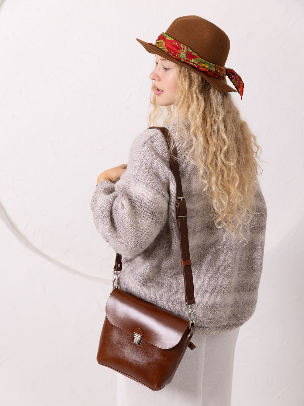 Portefeuille en cuir gingembre orangé tenu en main, photo lifestyle