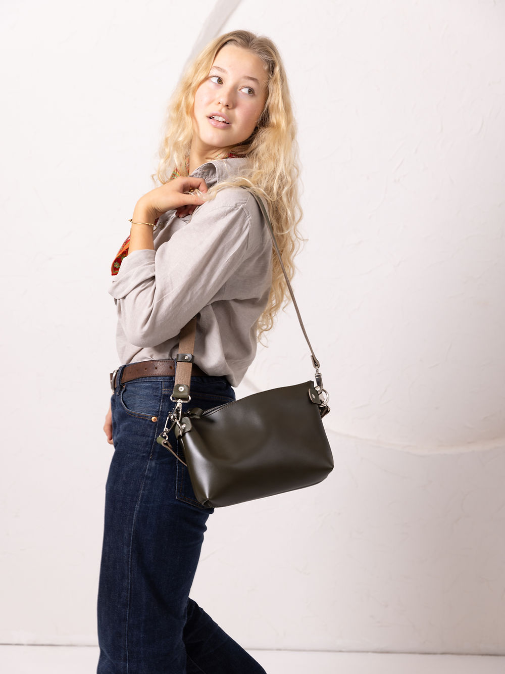 Sac à deux anses TOMMY TOKS VISOKS en cuir noir, porté en bandoulière sur chemise grise et jean brut