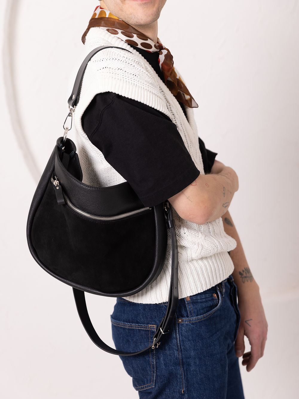 Sac à main STELLA TOKS VISOKS en cuir noir et daim, porté en bandoulière sur gilet en maille écru et foulard à pois