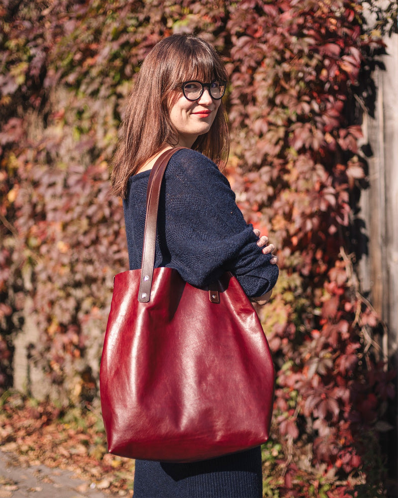 Sac cabas en cuir bordeaux Stella Soomlais, porté à l'épaule par une femme en extérieur